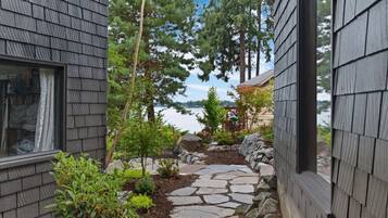 A stone pathway leading to a house with a view of a lake.