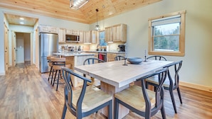 A spacious kitchen with wooden cabinets, a stainless steel refrigerator, and a large island with seating. - Hot Tub | Fire Pit | Mtn Escape Near Sunday River (Bethel)