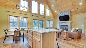 A spacious living area with a large wooden ceiling, a stone fireplace, and a television mounted above it. - Hot Tub | Fire Pit | Mtn Escape Near Sunday River (Bethel)