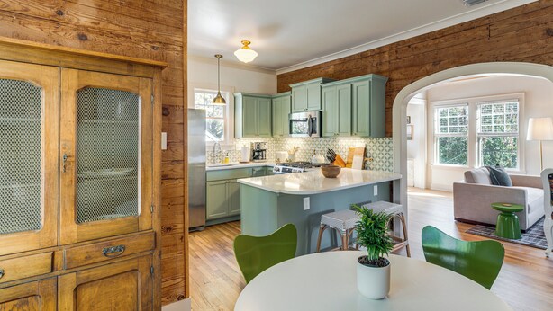 Une cuisine avec des meubles en bois, un îlot central et un coin repas avec des chaises.