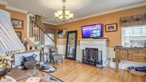 Ein Wohnzimmer mit Kamin, Fernseher, Treppe und einer Chandelier.