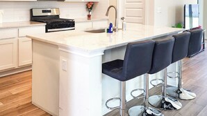 A kitchen with a central island, stainless steel appliances, and bar stools. - Buda Business-Ready House: Office, Home Gym & Yard (Buda)