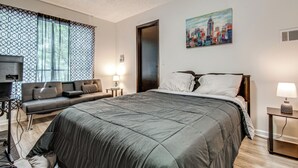 Et hotelværelse med en seng, en sofa, et billede og et fjernsyn.