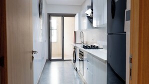 A narrow kitchen with a built-in oven, a sink, and a refrigerator. - Premium central duplex 120m2 + Garage and high-speed WiFi (Dar-el-Beida)