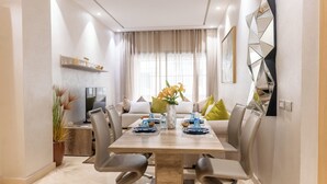 A modern dining area with a wooden table, grey upholstered chairs, and a vase with flowers. - Premium central duplex 120m2 + Garage and high-speed WiFi (Dar-el-Beida)