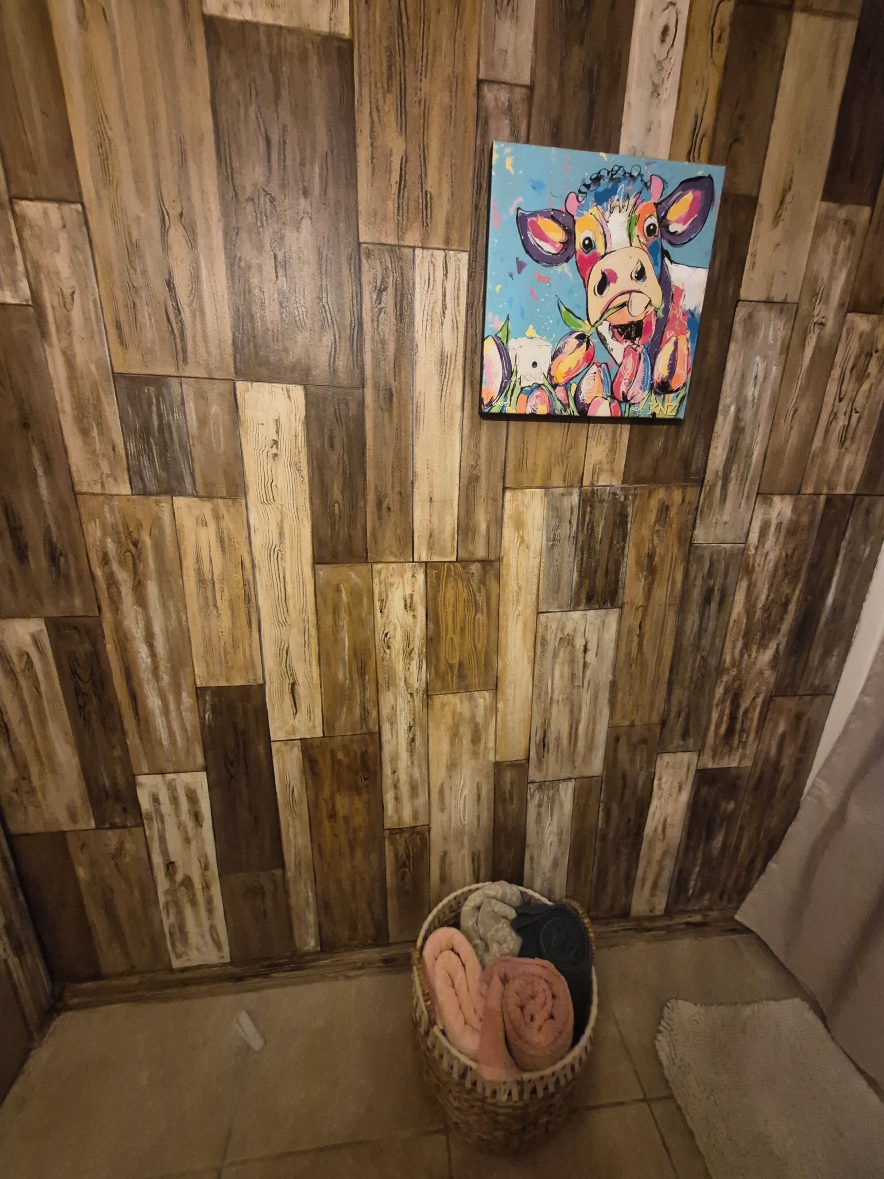 A room with a wooden wall panel design and a painting of a cow.