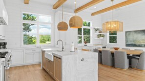 A modern kitchen with white cabinetry, a central island, and large windows. - Spacious Coastal Retreat Near Inlet Beach With Bikes, Balconies & Modern Design Bluewater View by Avantstay (Panama City Beach)
