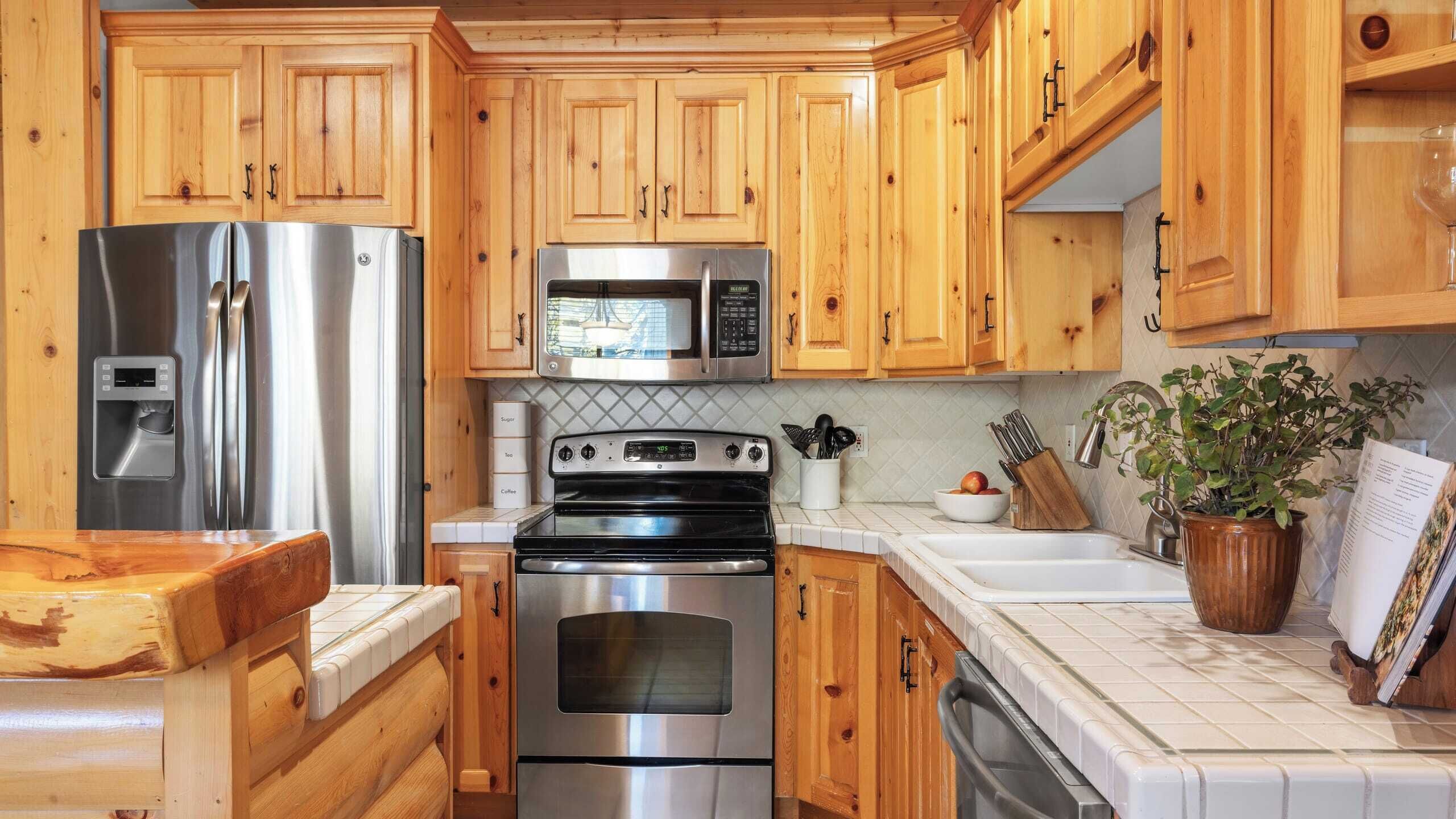 A kitchen with wooden cabinets, stainless steel appliances, a microwave, and a stove.