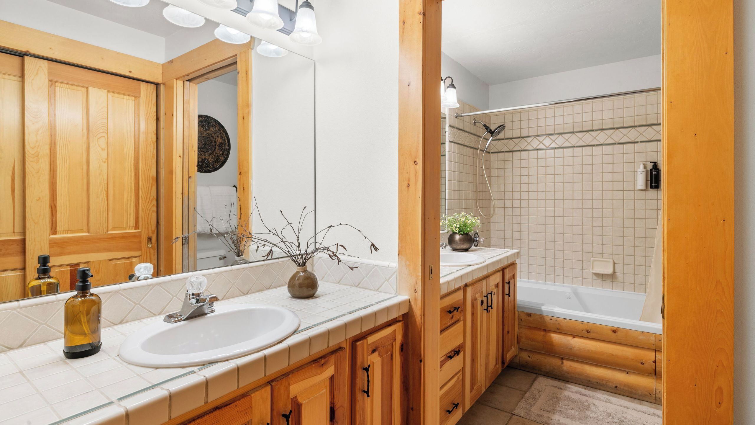 Ein Badezimmer mit Holzausstattung, einem Waschbecken, einem Spiegel, einer Dusche und einer Badewanne.