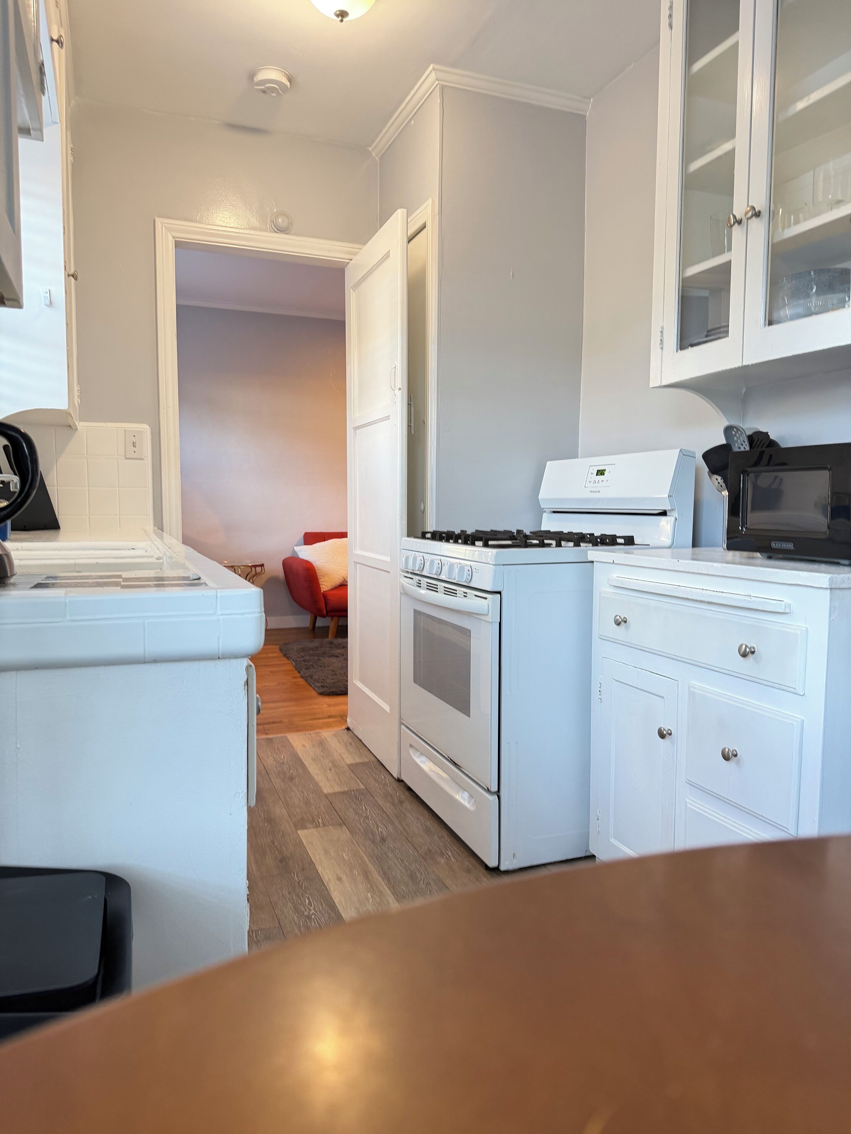 A compact kitchen with white cabinetry, a stove, a microwave, and a refrigerator.