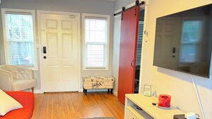 Un salon comprenant un canapé, un téléviseur, une petite table avec une bougie et un placard à portes coulissantes.