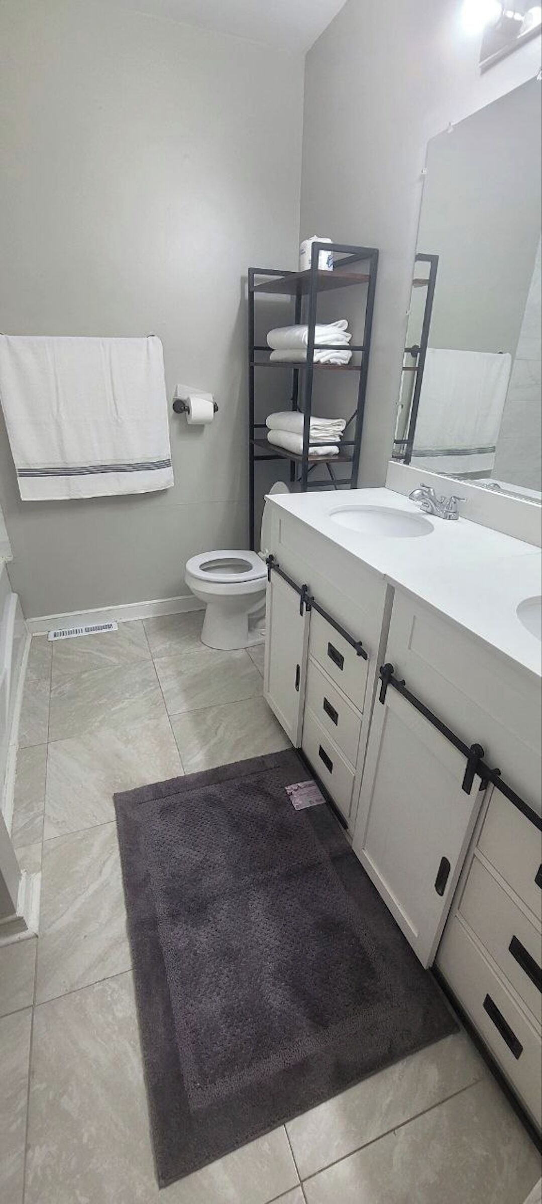 Un baño con inodoro, lavamanos y toallero.