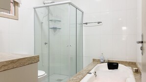 Un baño moderno con ducha de vidrio, una bañera blanca y encimera de mármol.