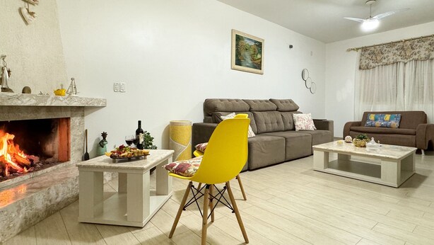 Una sala de estar con chimenea, un sofá, un sillón amarillo y una mesa de centro.