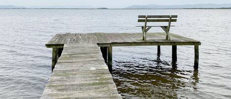 A wooden pier extending into calm water with a bench at the end.