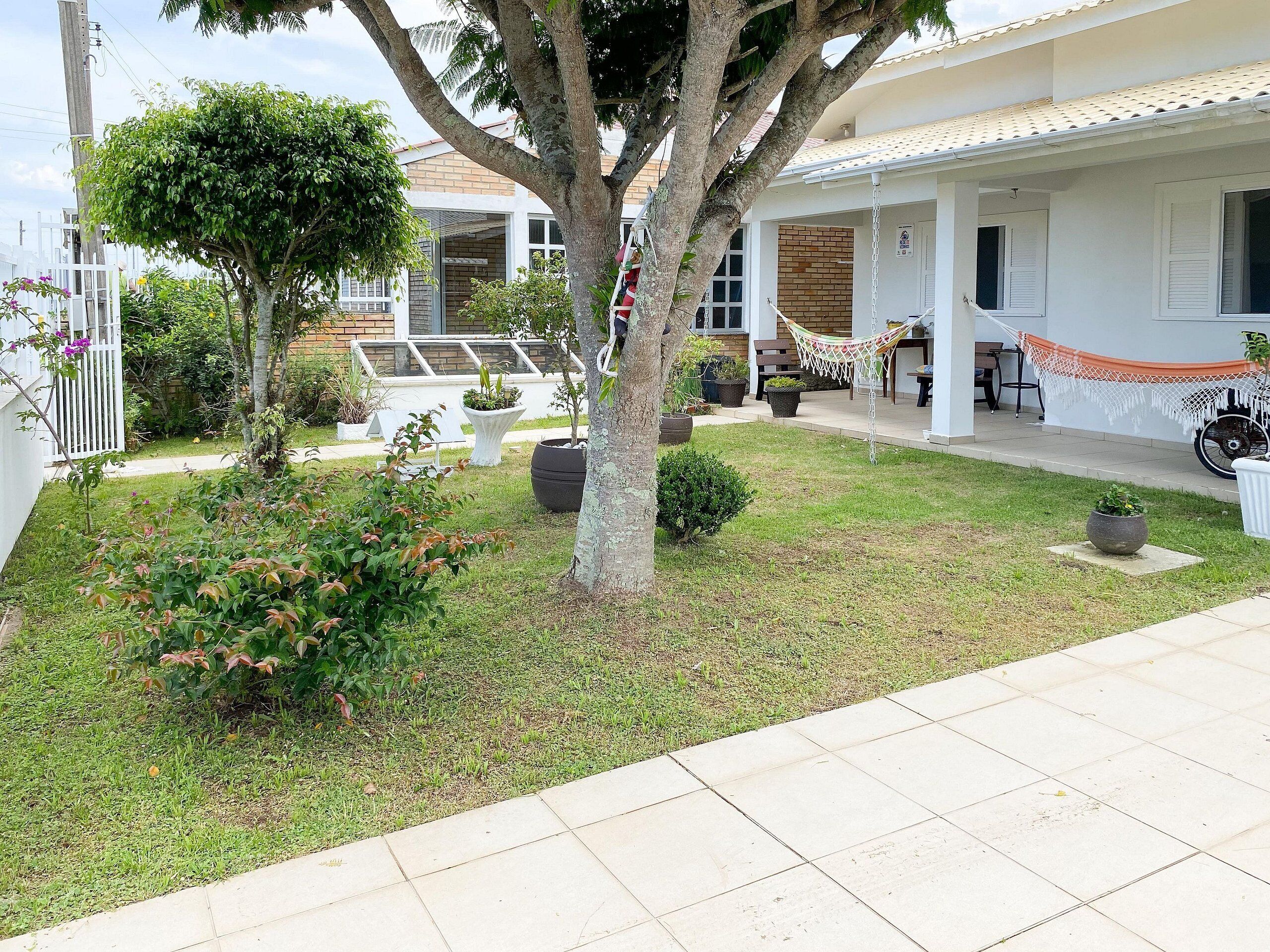 Um imóvel residencial com gramado bem cuidado, uma rede e um espaço de varanda.