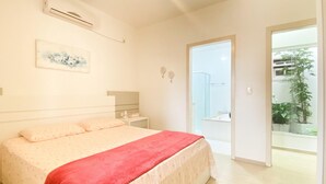 Un dormitorio con cama, mesita de noche y puerta que da al baño.