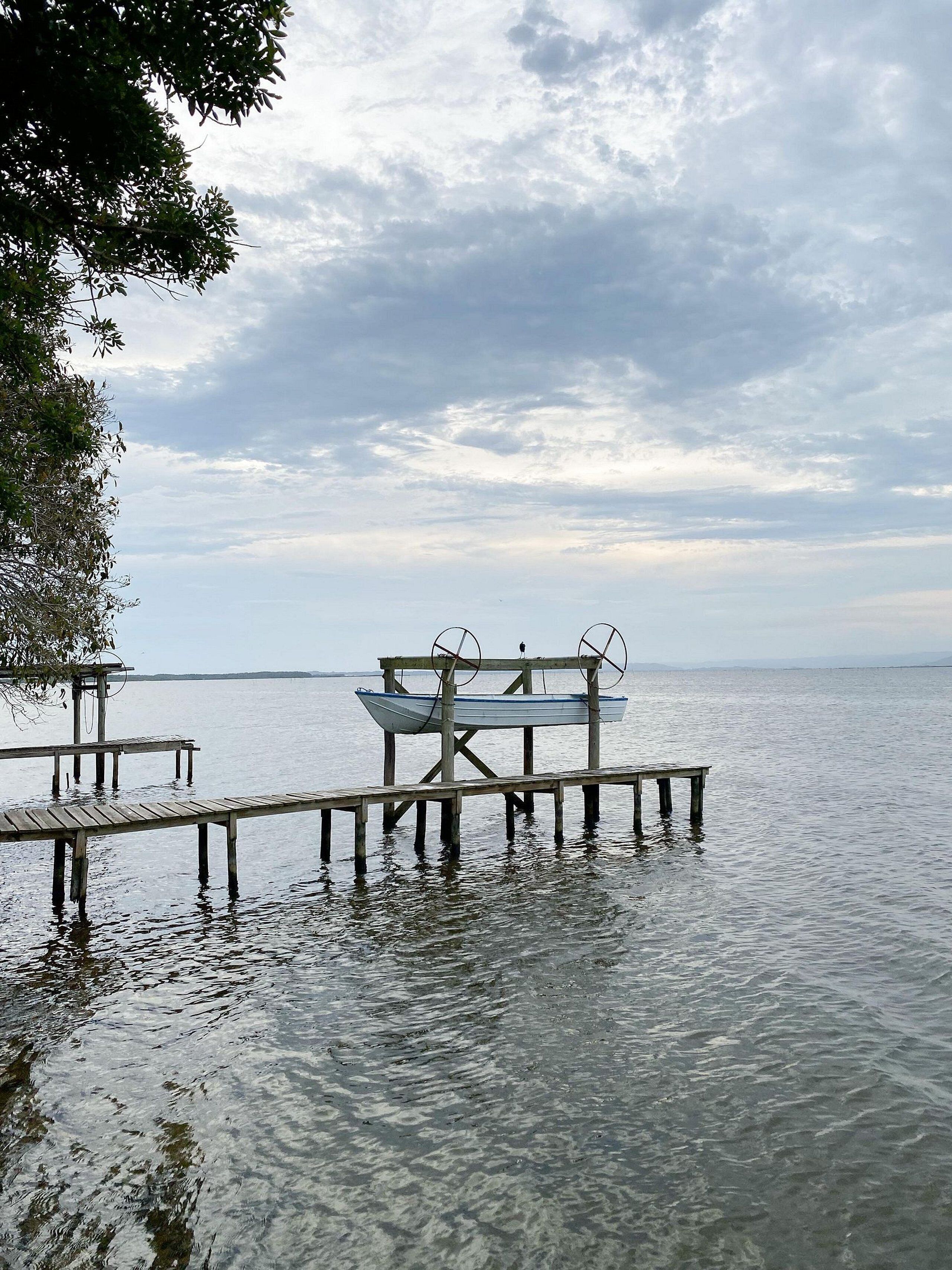 A wooden pier extending into calm water with a boat docked on it.