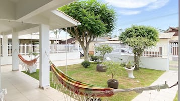 Un patio coperto con un'amaca, un piccolo cane e un prato curato con piante in vaso.