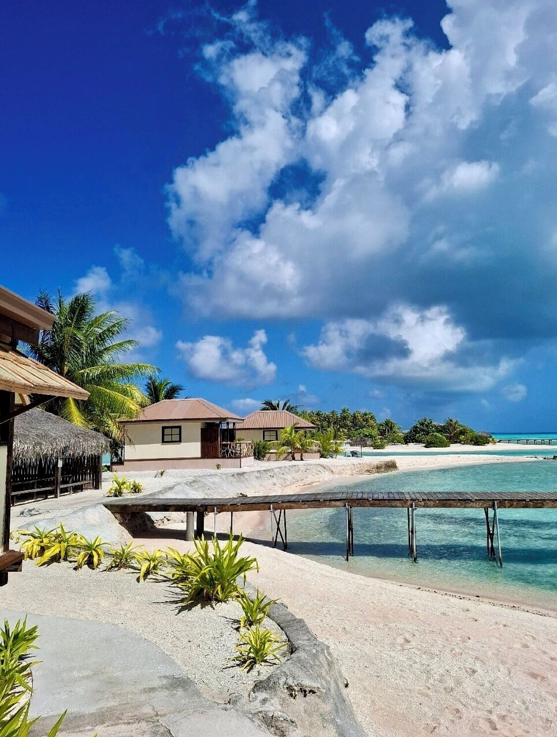 A tropical resort with overwater bungalows, clear turquoise waters, and a sandy beach.