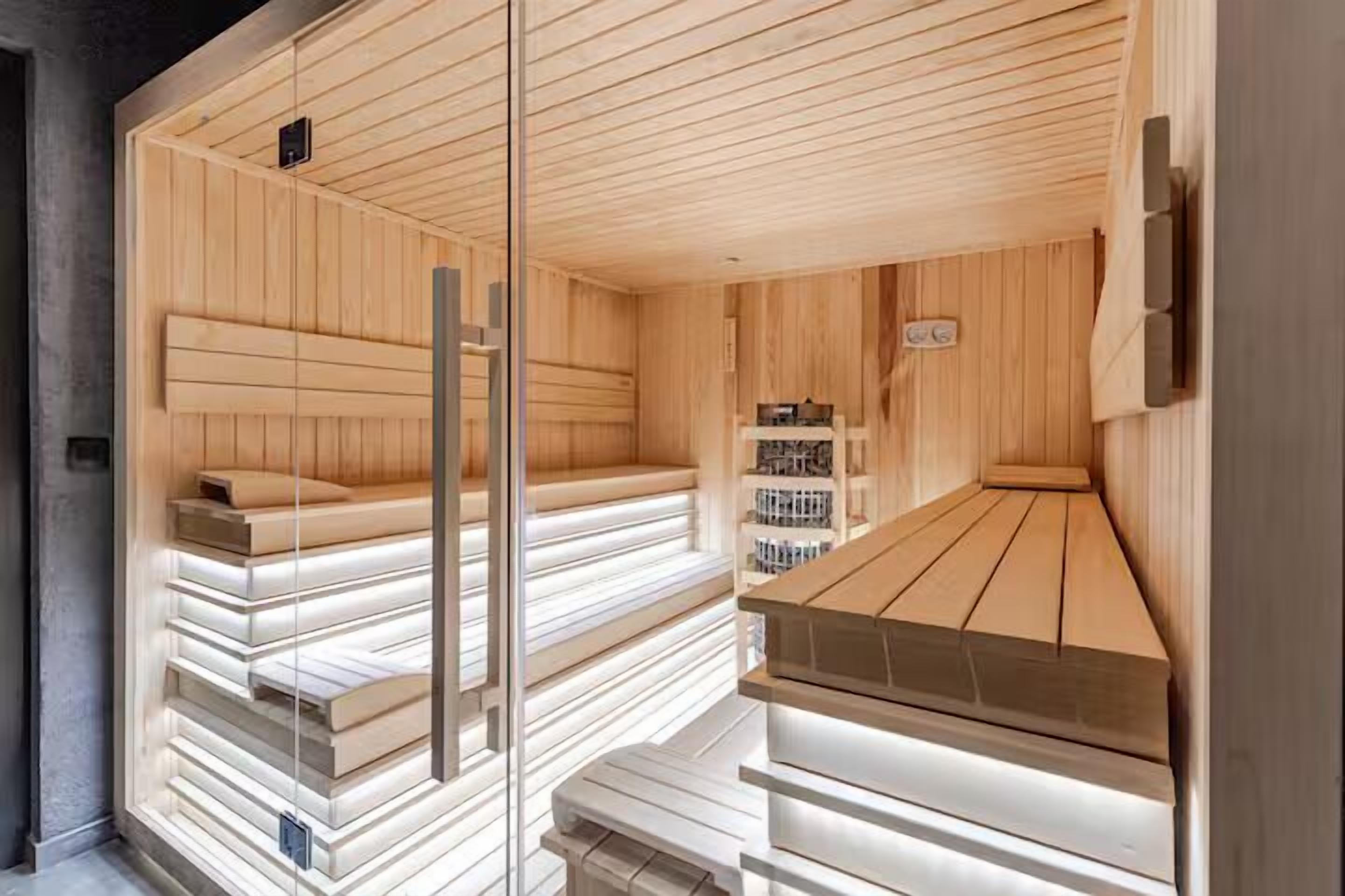 Uma sauna com bancos de madeira e divisória de vidro.