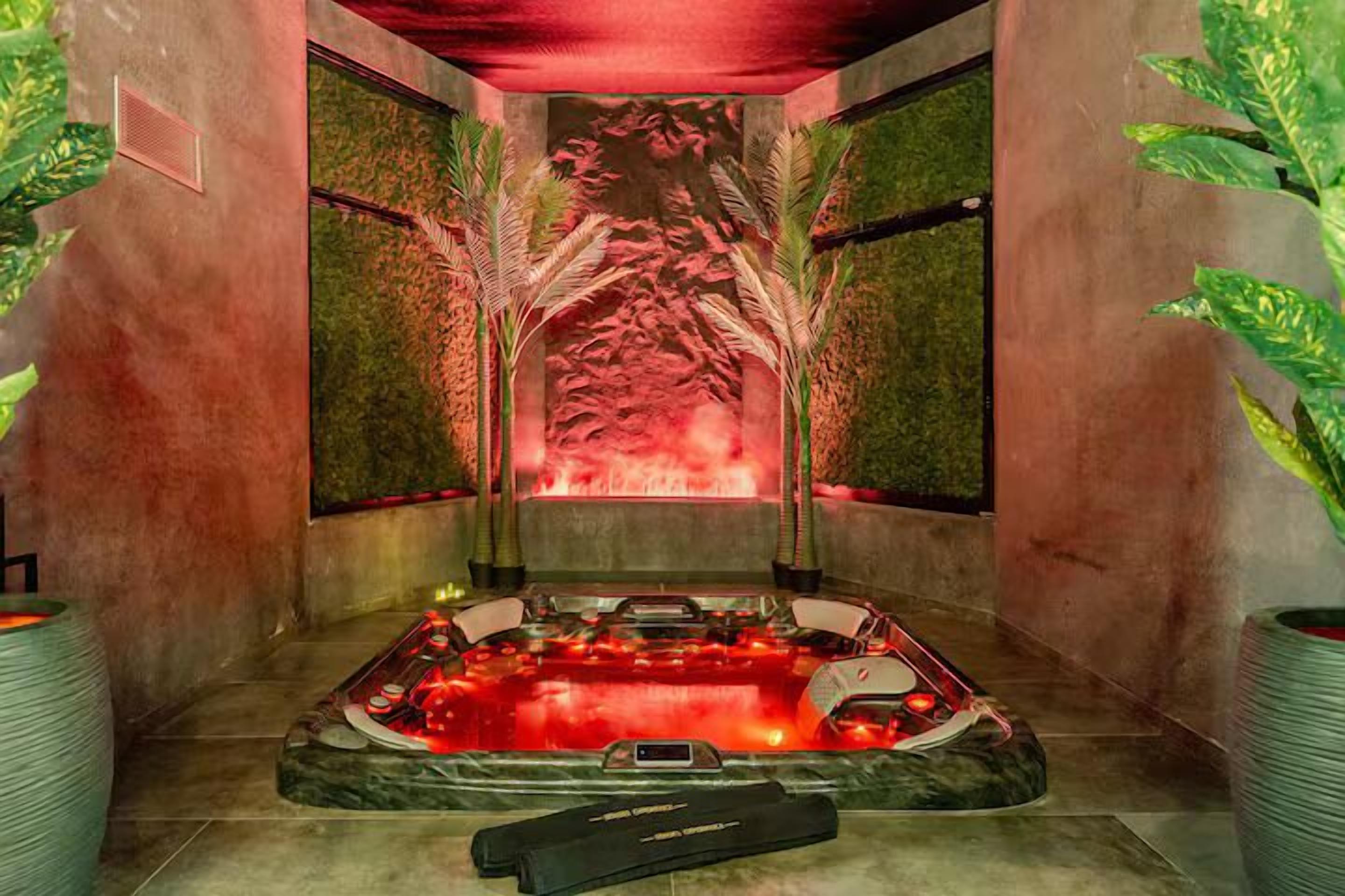 Een spa ruimte met een jacuzzi, een massagetafel en een muur met een abstract rood ontwerp.