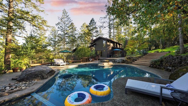 A swimming pool with lounge chairs and inflatable rings, surrounded by trees and a house. - 10-acre Wellness Retreat, Pool, Sauna, Ceremony Tent Fable Sonoma by Avantstay (Santa Rosa)