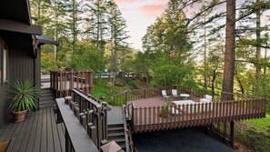 A wooden deck with outdoor furniture, surrounded by a wooden fence and trees.
