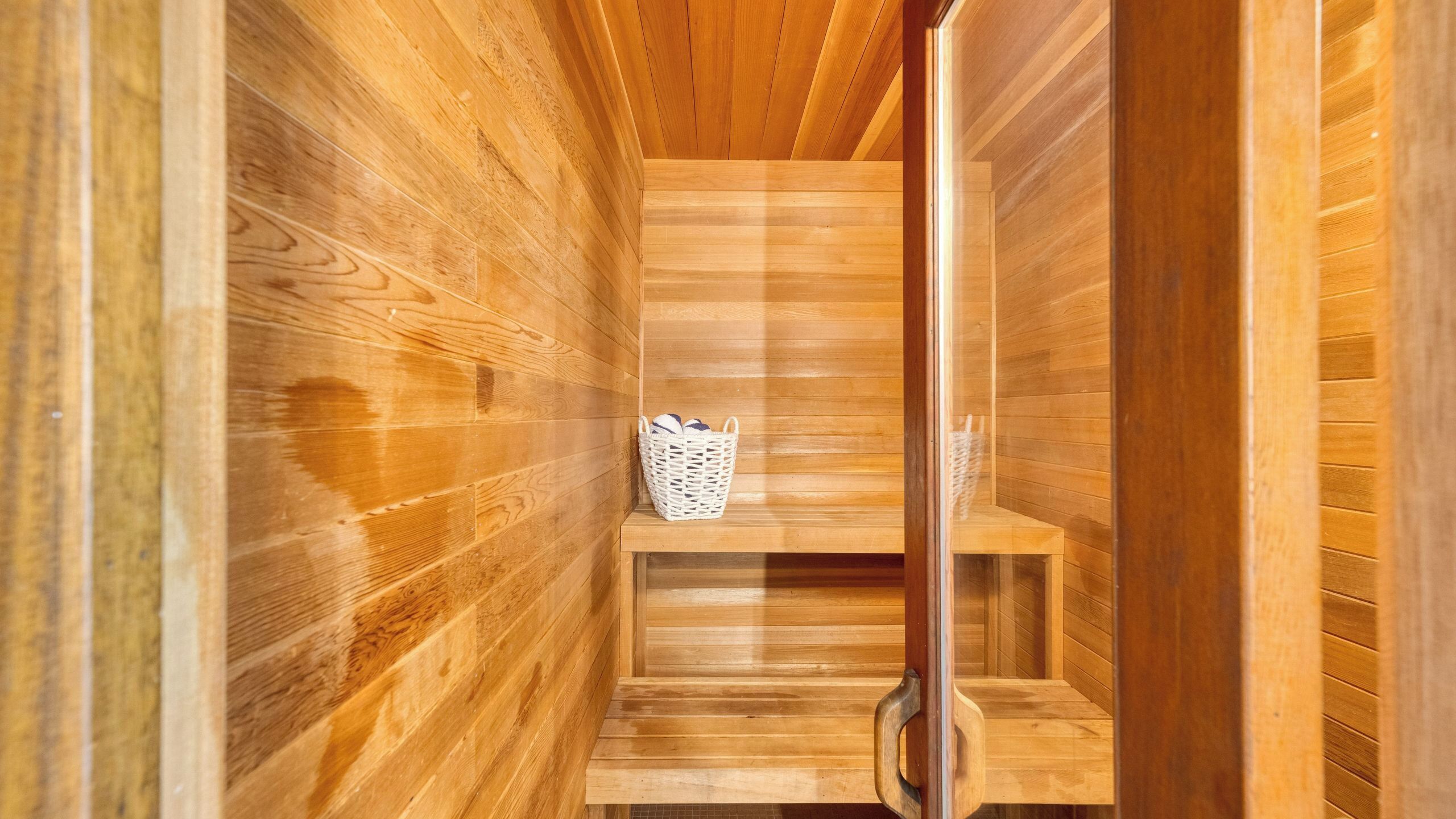 Una sauna de madera con un banco y una cesta.