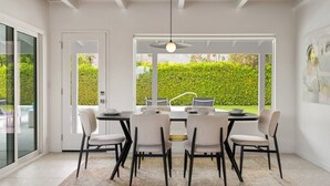 A modern dining area with a round table, six chairs, and a pendant light.