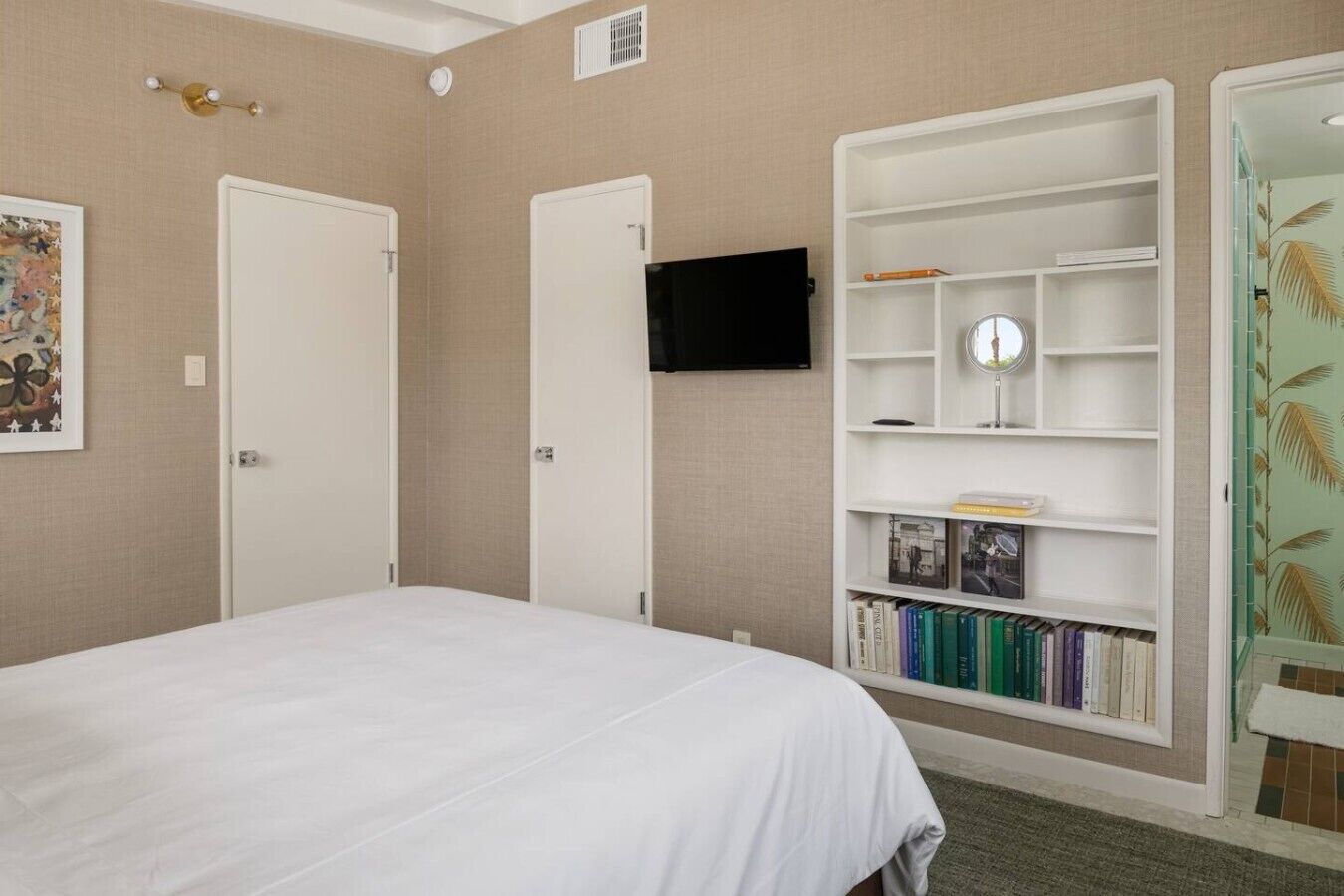 Une chambre à coucher avec un lit, une bibliothèque, un téléviseur et une porte.
