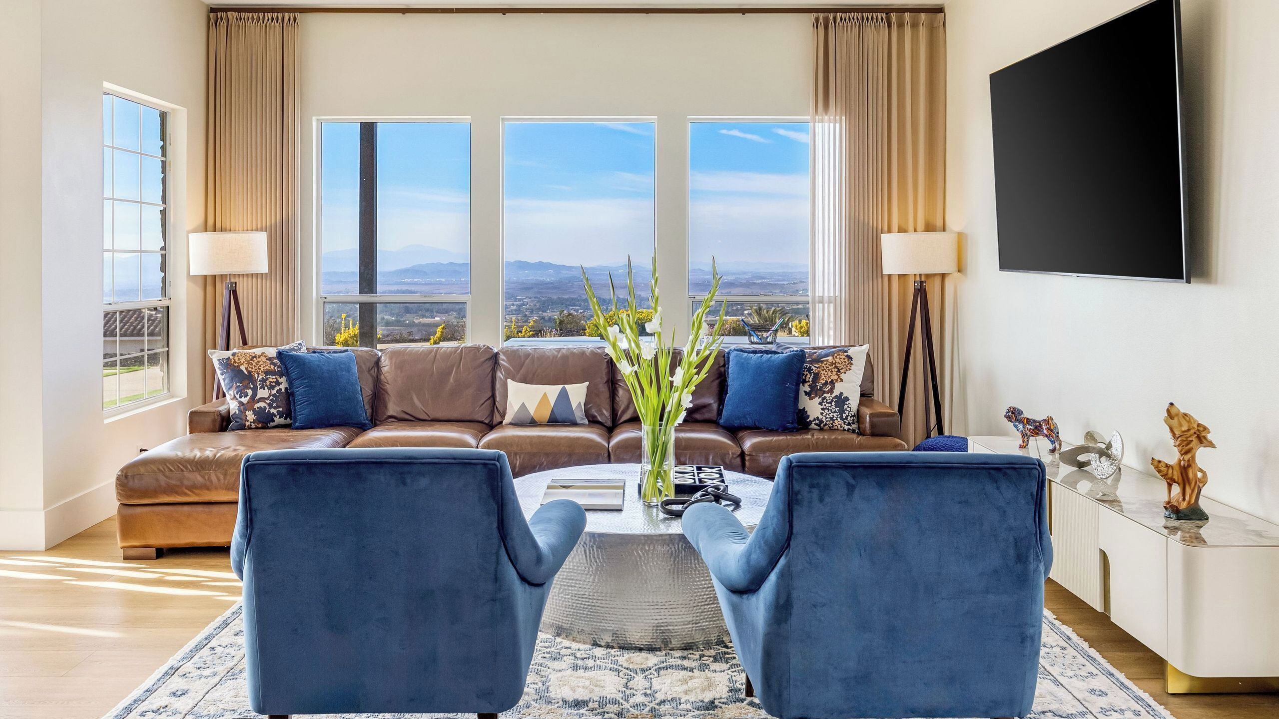 A living room with a sofa, two armchairs, a coffee table, and a TV.