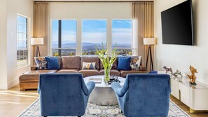 A living room with a sofa, two armchairs, a coffee table, and a TV. - Hilltop Estate w/ Tennis Court, Pool, Sauna, Game Room, Theater, Panoramic Views Via de Oro Estate by Avantstay (Temecula)