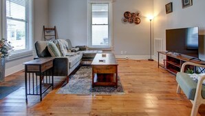 A living room with a sofa, coffee table, TV stand, and ceiling fan. - Park Avenue Retreat (Hot Springs)