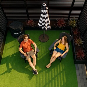 A rooftop patio with two lounge chairs, a black and white striped umbrella, and potted plants. - 3BR | Rooftop&Yard | West Seattle | Sophari Home A (Seattle)