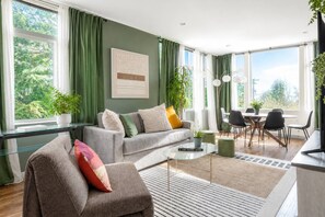 A modern living room with a sofa, a coffee table, and a dining area with chairs. - 3BR | Rooftop&Yard | West Seattle | Sophari Home A (Seattle)