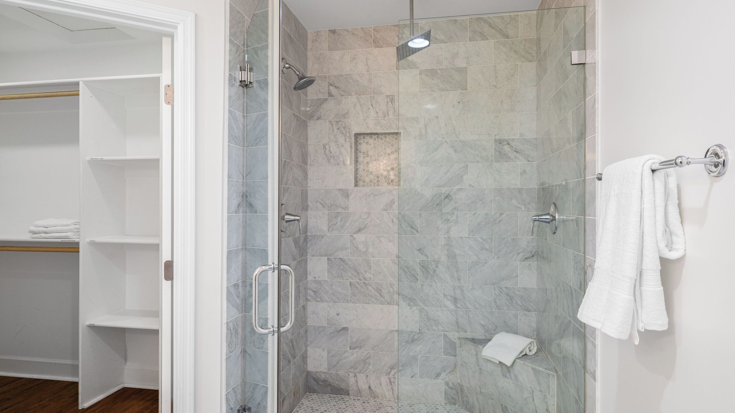 Une douche à l’italienne avec des parois en verre, une barre d’appui et un porte-serviettes.