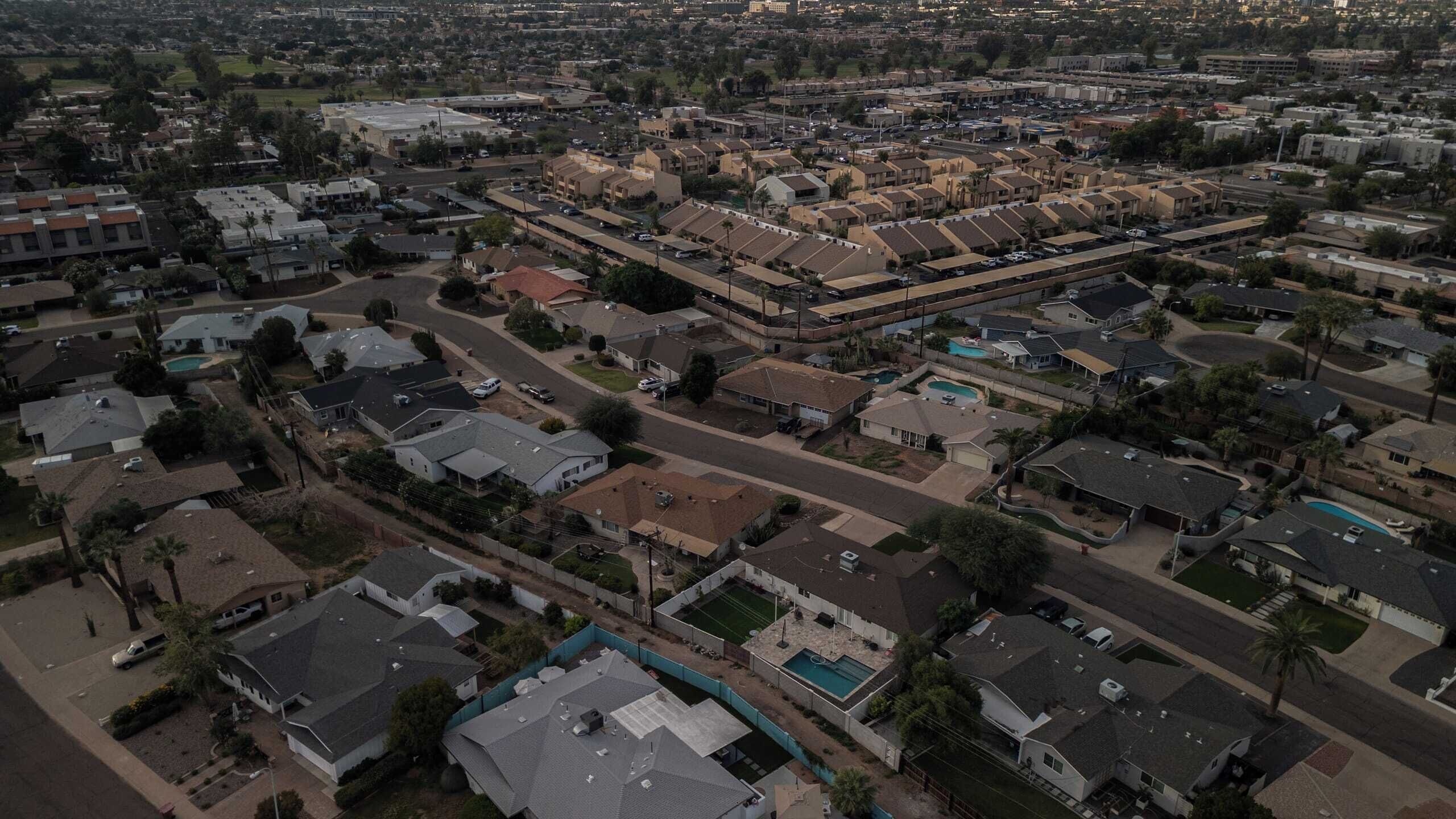 An aerial view of a residential neighborhood with houses, streets, and a large building in the distance.