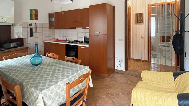 Una cocina compacta con armarios de madera, una mesa de comedor con sillas y un sofá amarillo.
