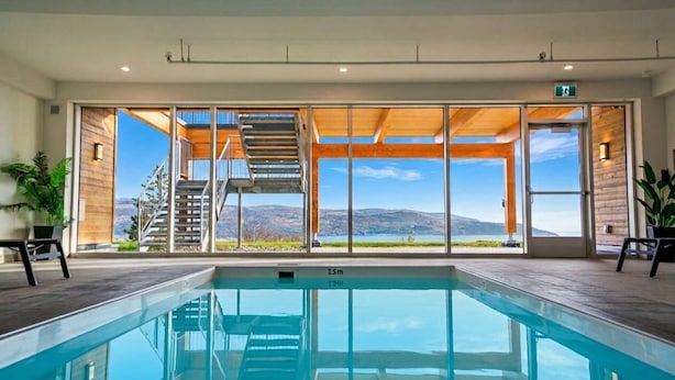 Una piscina con vistas a un paisaje montañoso a través de grandes puertas de cristal.
