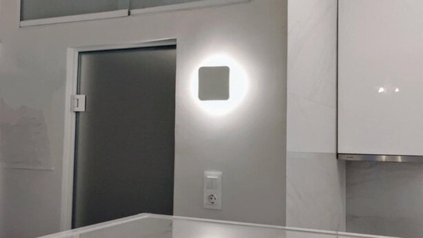 Une cuisine moderne avec des meubles blancs, un réfrigérateur en acier inoxydable et un éclairage encastré.