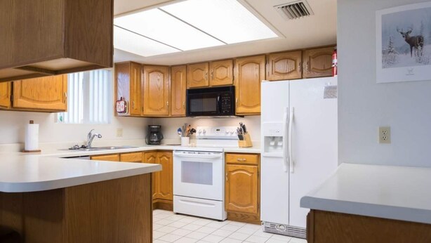 Une cuisine avec des meubles de rangement en bois, un four à micro-ondes, une cuisinière et un réfrigérateur.