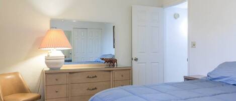 A bedroom with a bed, a dresser, a chair, and a lamp.
