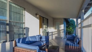 Eine überdachte Veranda mit einem blauen Sofa, Korbstühlen und einem kleinen Tisch.