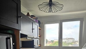 Eine kleine Küche mit Mikrowelle, Backofen und Spüle. Ein Fenster bietet einen Blick nach draußen.