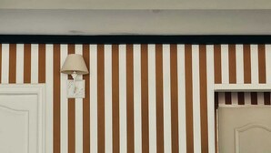 Ein Zimmer mit einer gestreiften Wand, einer weißen Tür und einer Lampe.