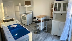 Una cucina compatta con fornello, forno e un piccolo angolo ristoro con sgabelli.