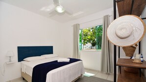 A bedroom with a bed, a ceiling fan, a window with curtains, and a view of greenery outside. - Casa com piscina a 250m da Praia PLH006 (Palhoça)