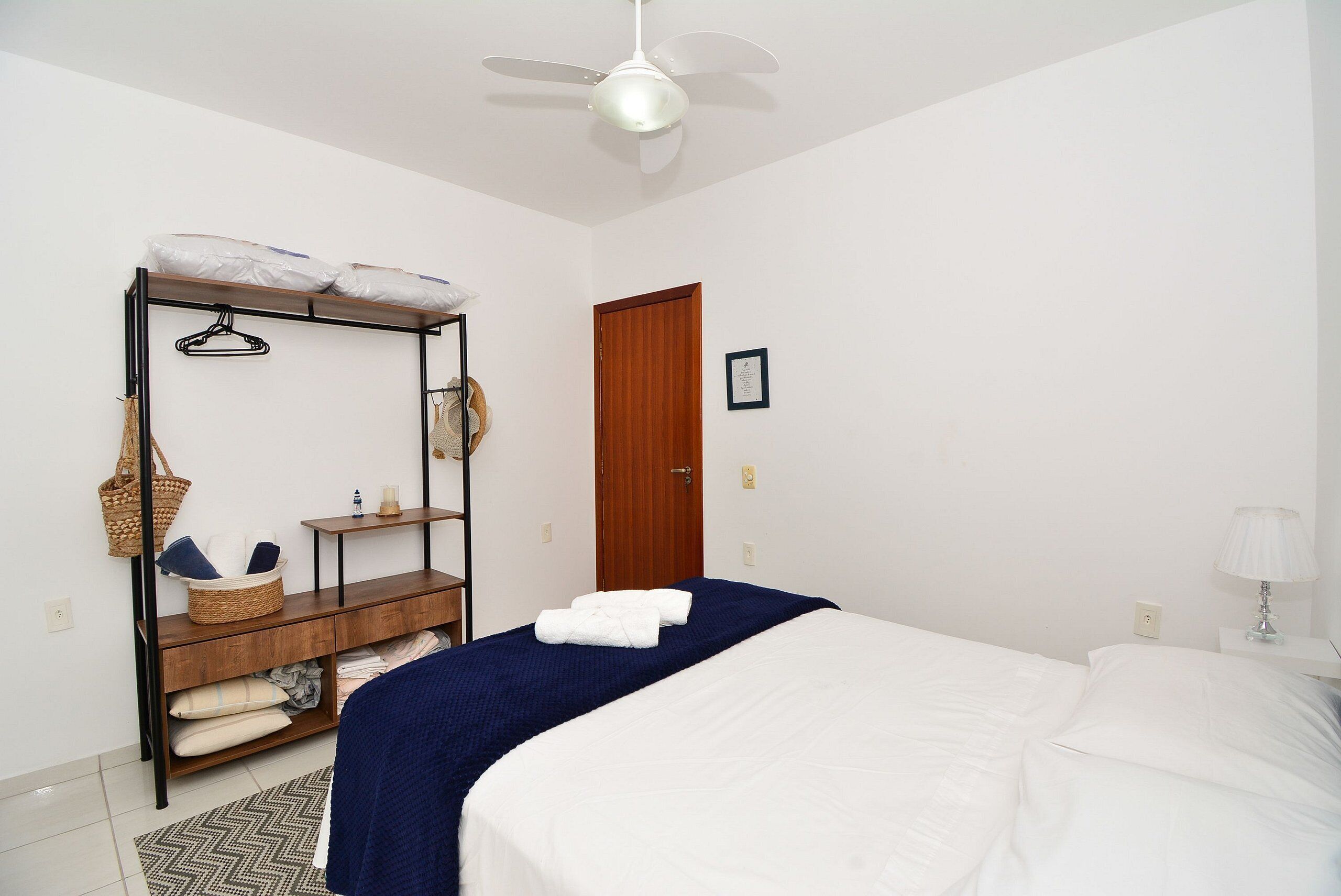 Ein Schlafzimmer mit Bett, Kleiderschrank, hängender Korb und Deckenventilator.
