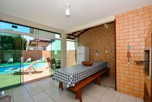 Una habitación con una mesa a cuadros, una banca, un muro de ladrillo y vistas a una piscina.